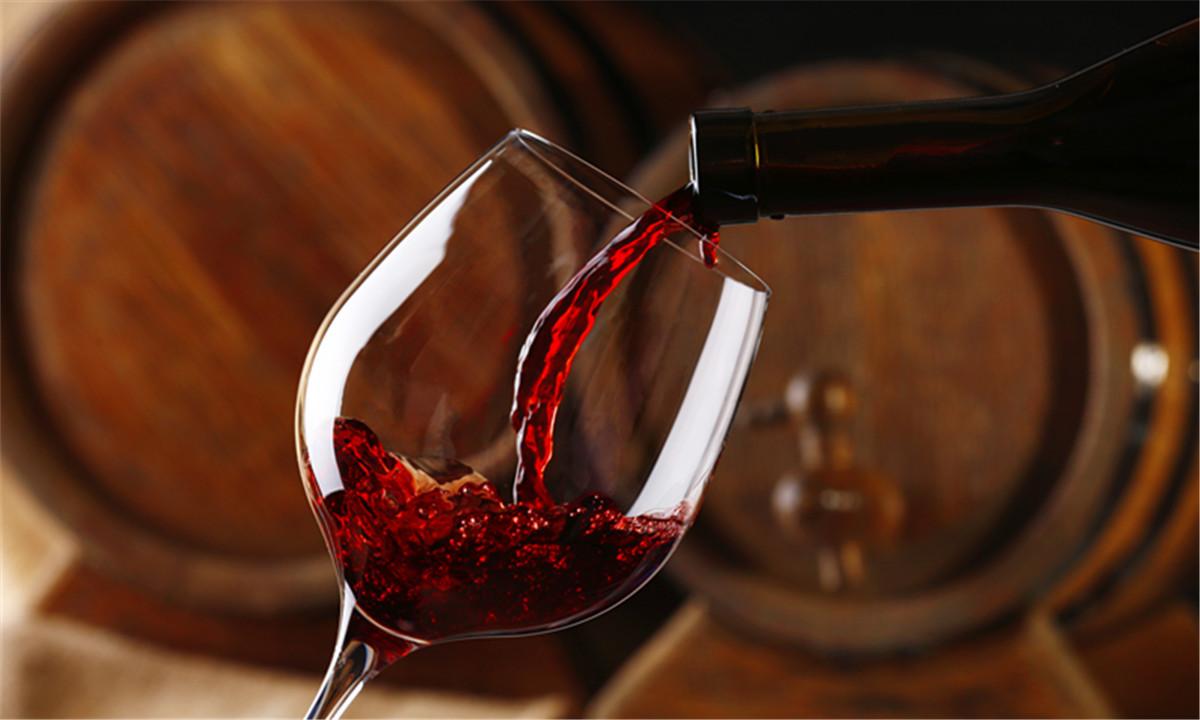 Rotwein wird in ein Glas eingeschenkt